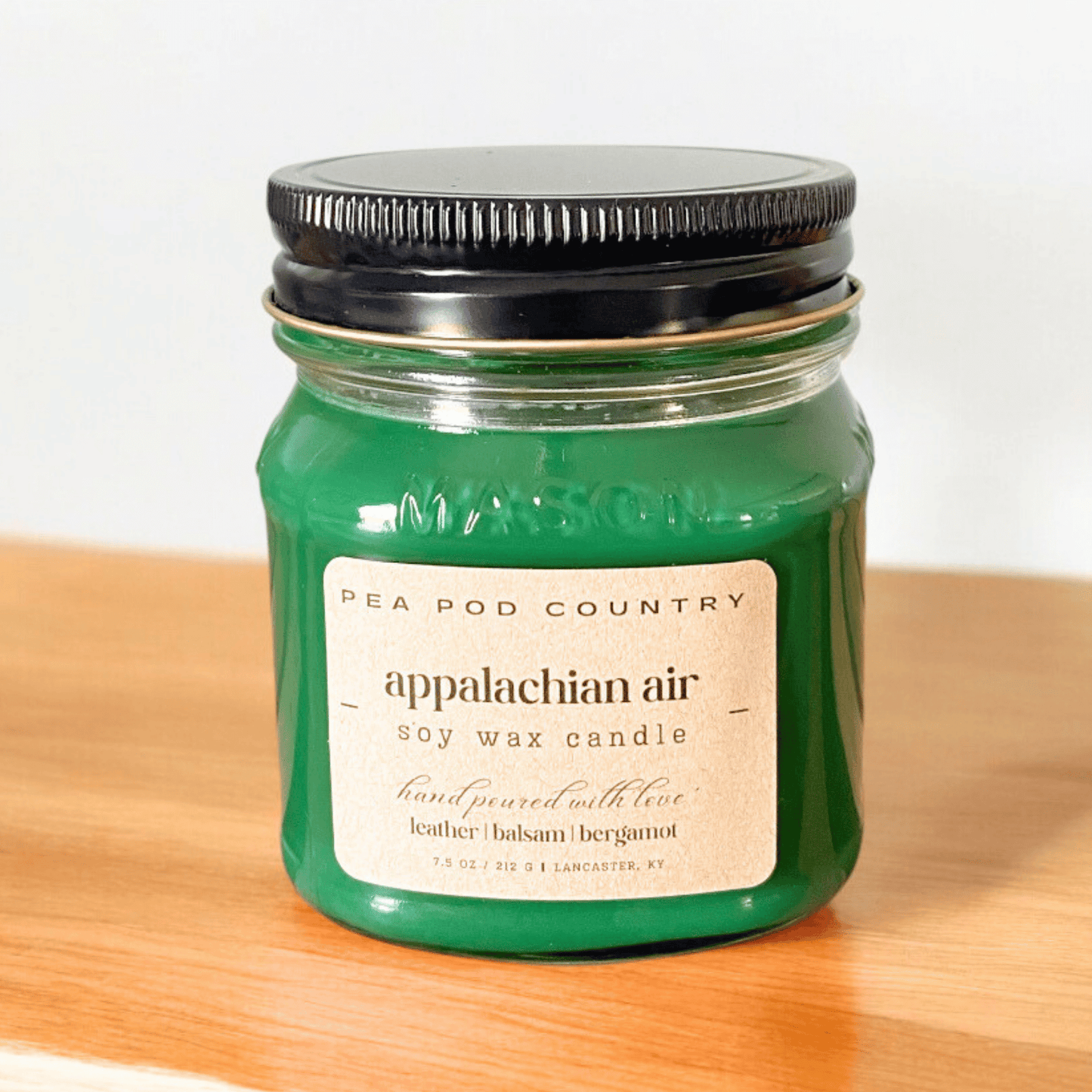 A 7.5 oz mason jar candle that is pine green in color.