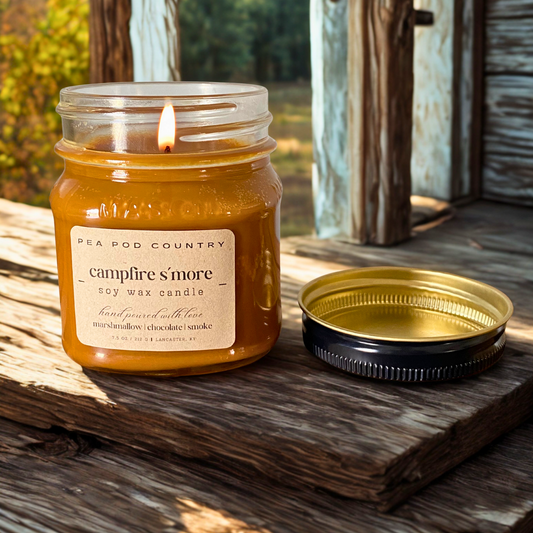 A lit 7.5 oz mason jar candle that is graham cracker brown in color sitting on an outdoor bench. 