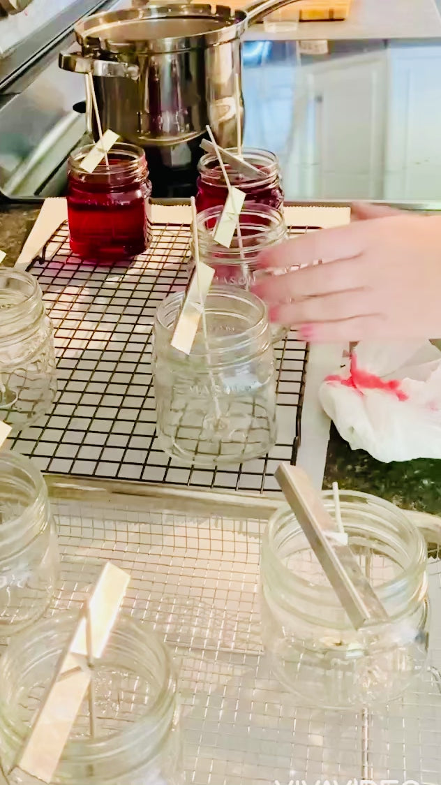 The process of hand pouring 7.5 oz mason jar candles. Red in color. 